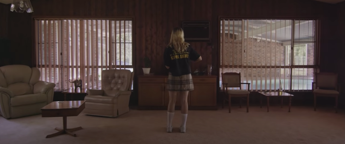 A picture of a woman wearing a class sweater in a modernist living room with her back turned to the camera